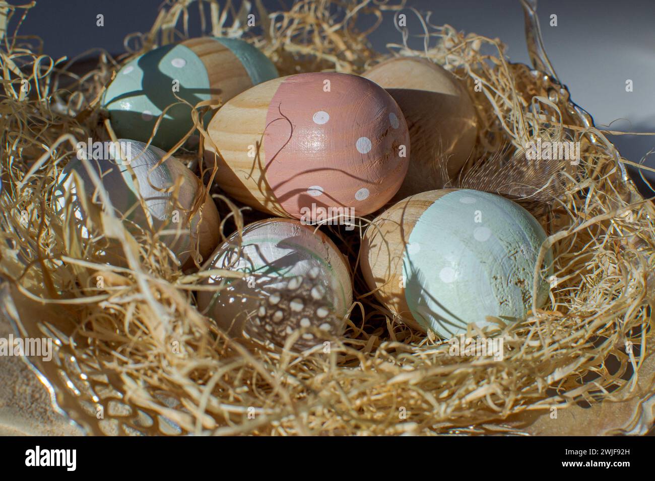 Multi-colored wooden Easter eggs lie in a paper nest Stock Photo