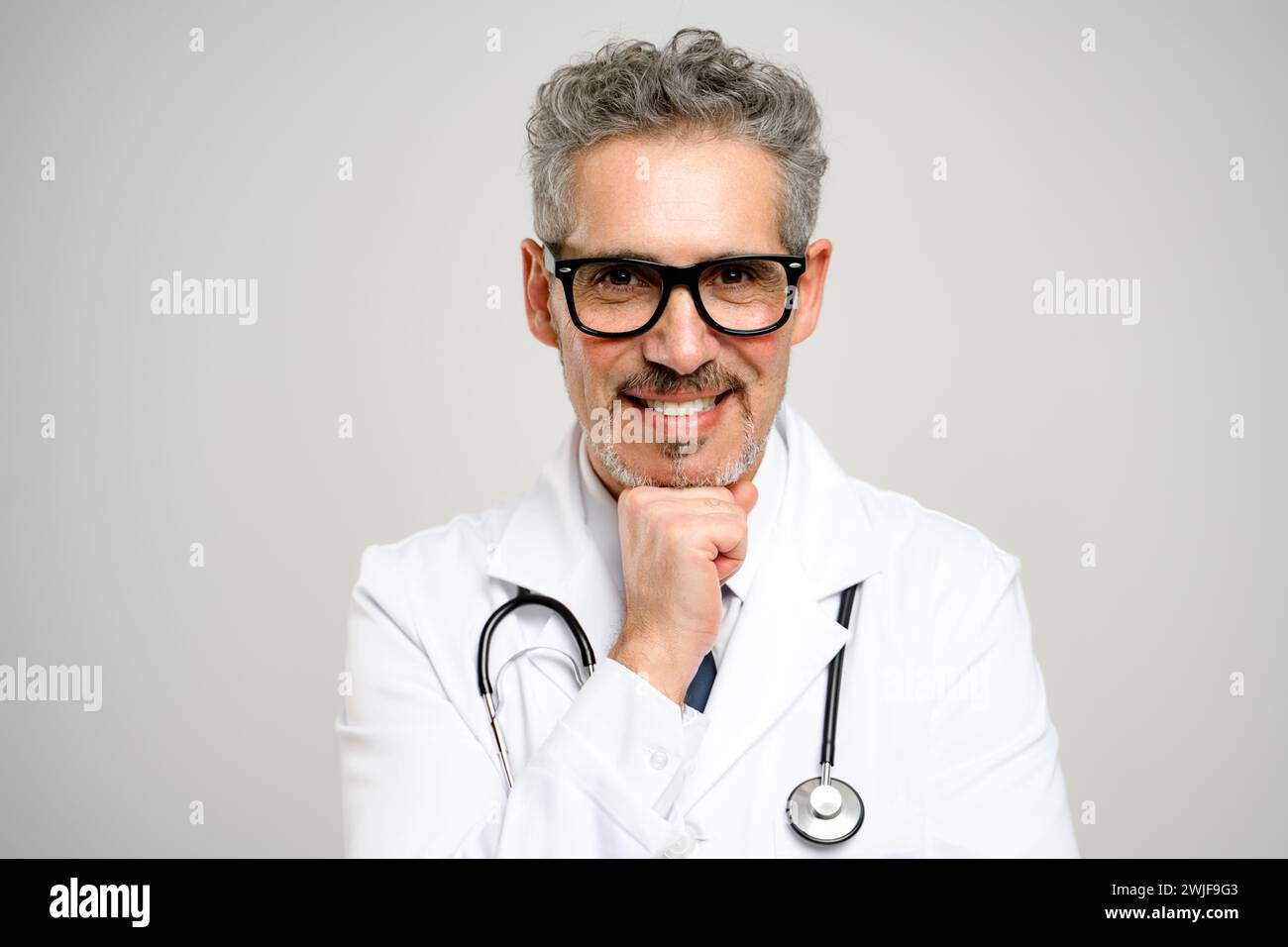 This image captures a senior doctor with glasses, posing thoughtfully ...