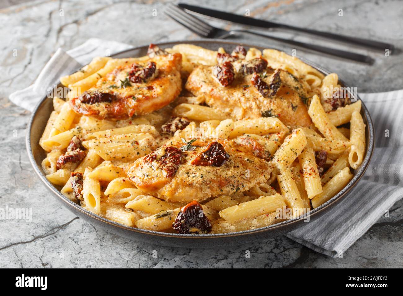 Marry Me Chicken penne with creamy pasta, tender chicken breast, parmesan cheese, sun-dried tomatoes, and herbs closeup on the plate on the table. Hor Stock Photo