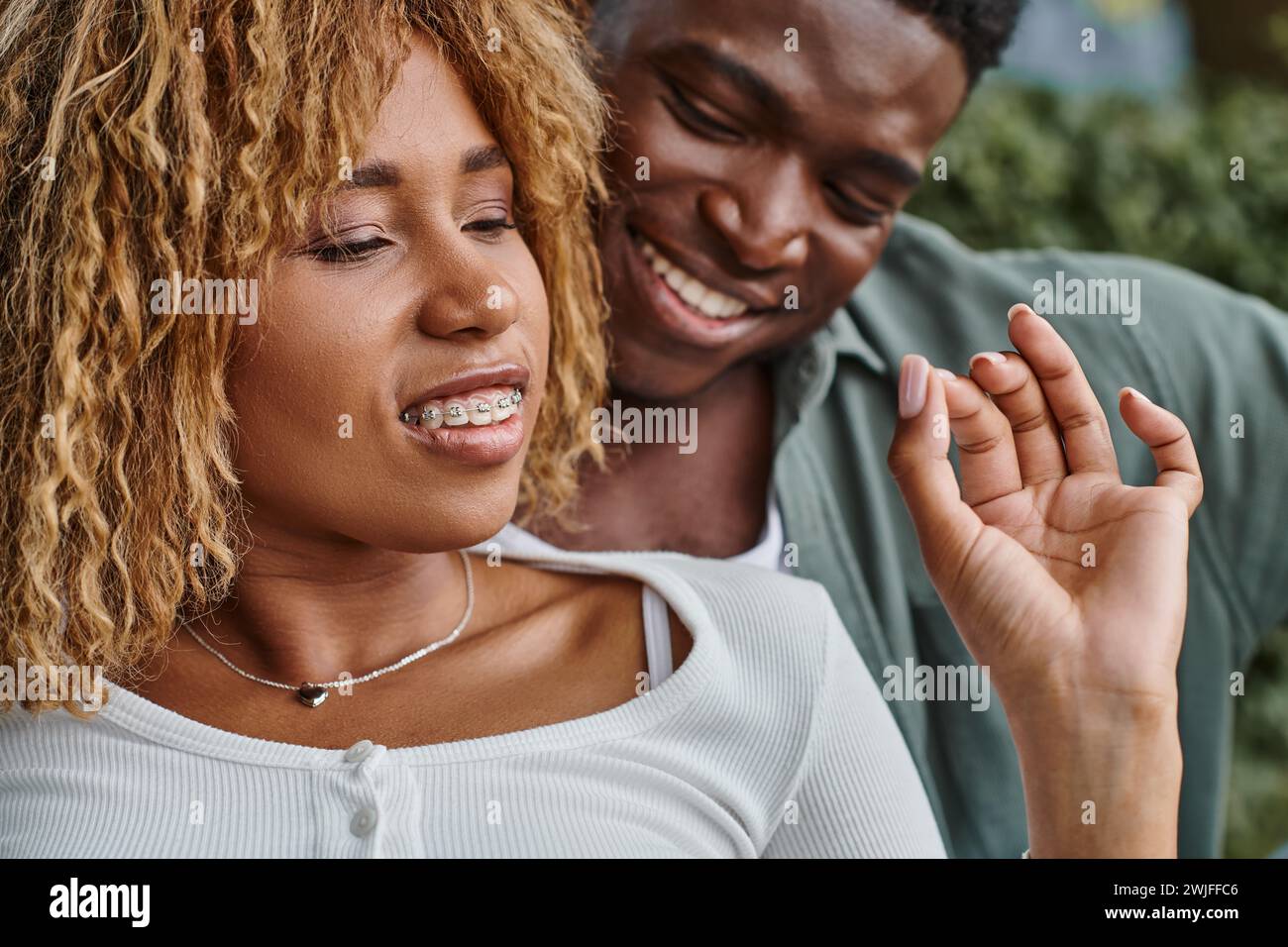 excited african american woman in braces using sign language for