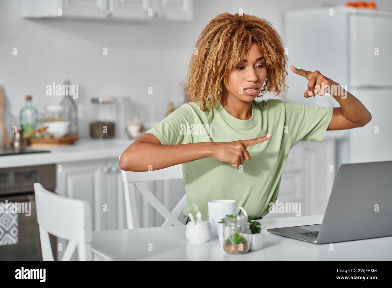 focused african american woman in braces using sign language during video call on laptop, gesture Stock Photo