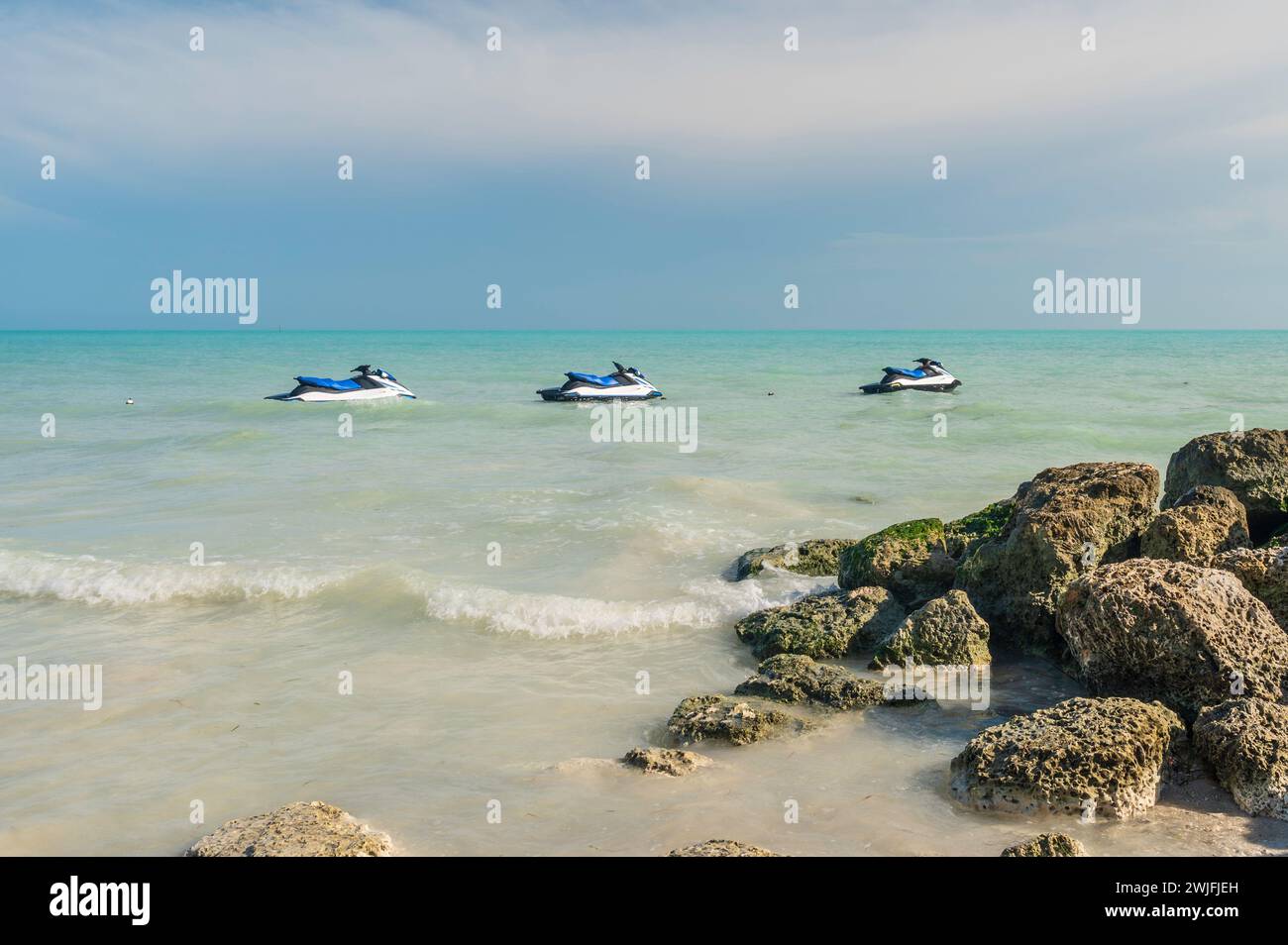 Three Jet Skis, moored just off shore. The day is sunny Stock Photo