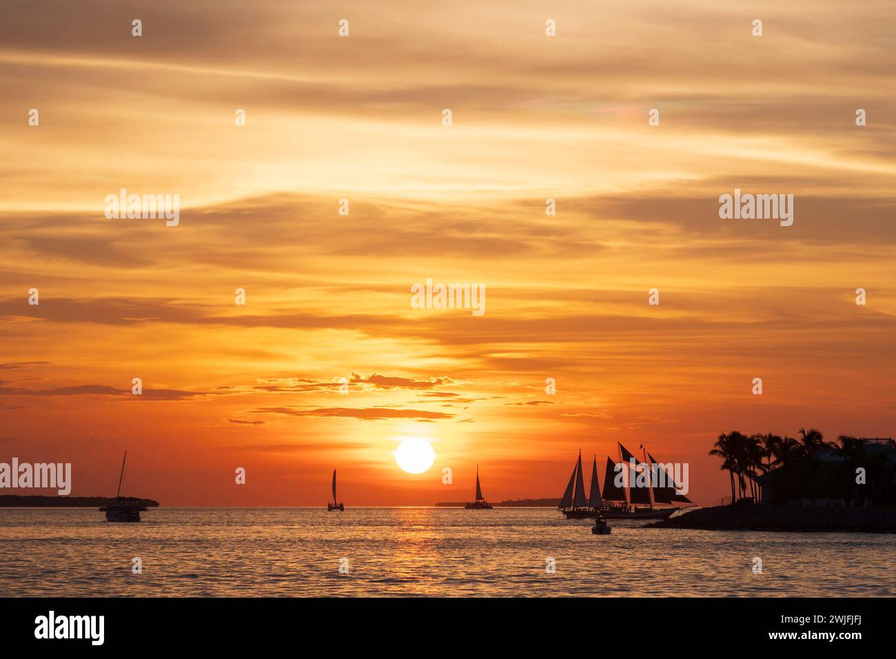 A spectacular sunset, off the coast of Key West, Florida, with sailing boats silhoutted against the orange sky Stock Photo