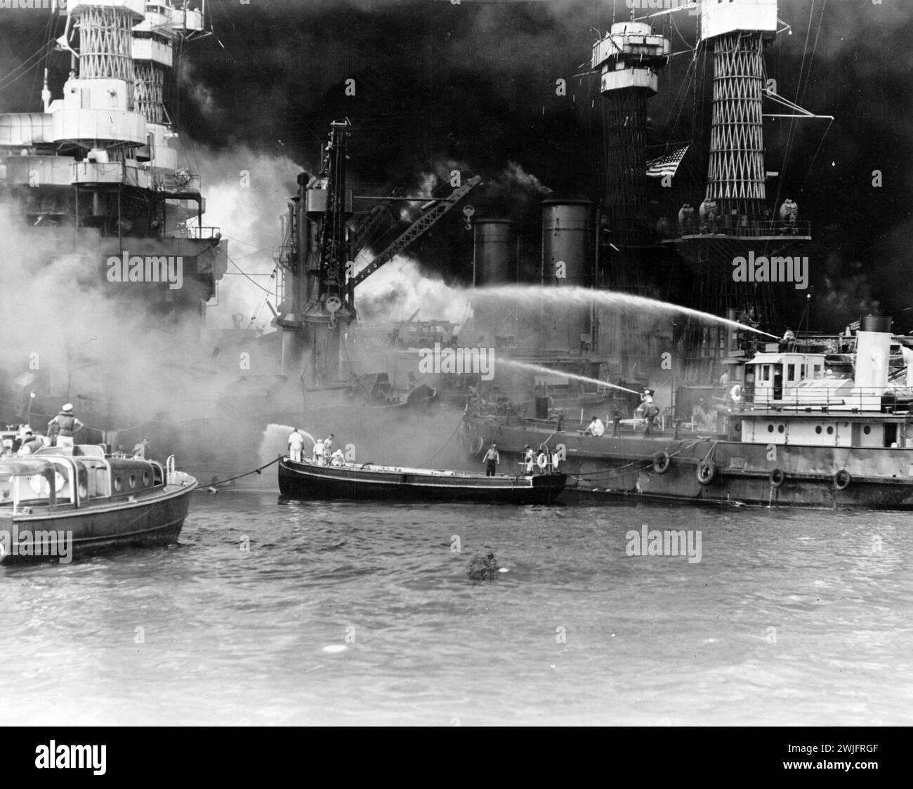World War II - Pearl Harbor, Hawaii, Dec 7, 1941. USS West Virginia aflame. Disregarding the dangerous possibilities of explosions, US sailors man their boats at the side of the burning battleship to better fight the flames Stock Photo