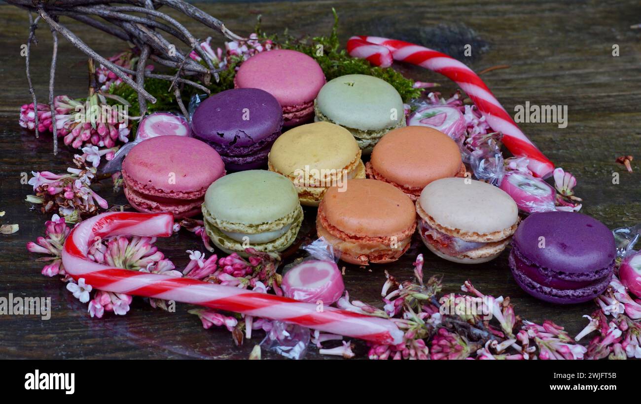 Colorful macarons on the form of a grape. Sugar canes. Pink blossoms. Stock Photo