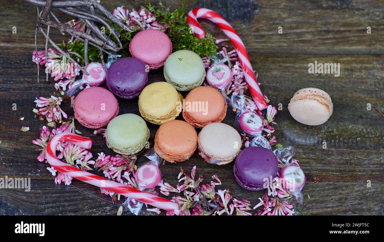 Colorful macarons on the form of a grape. Sugar canes. Pink blossoms. Stock Photo