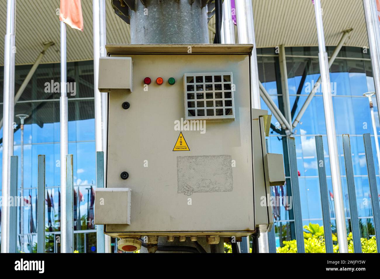 Urban caution: electrical panel box with warning sign on sleek street pole Stock Photo
