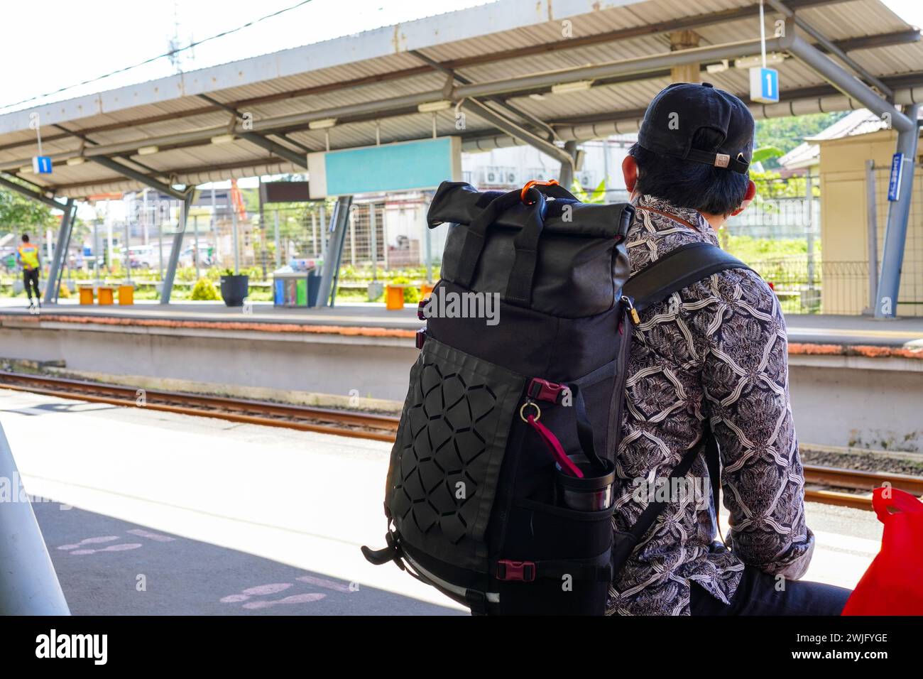 A backpacker is sitting waiting for the train to arrive at the train station Stock Photo