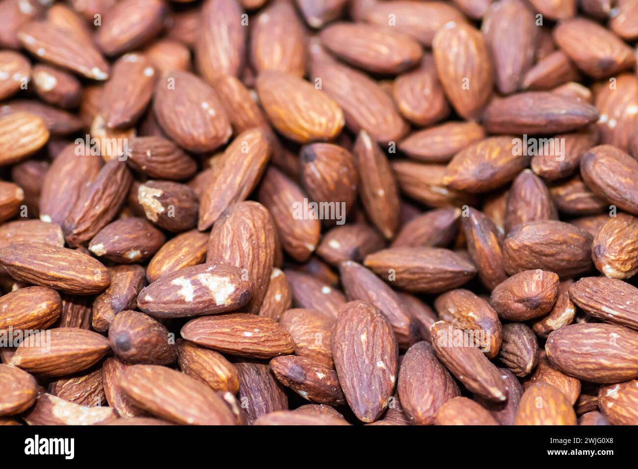 Close up roasted organic brown almond seeds on massive wooden table Stock Photo