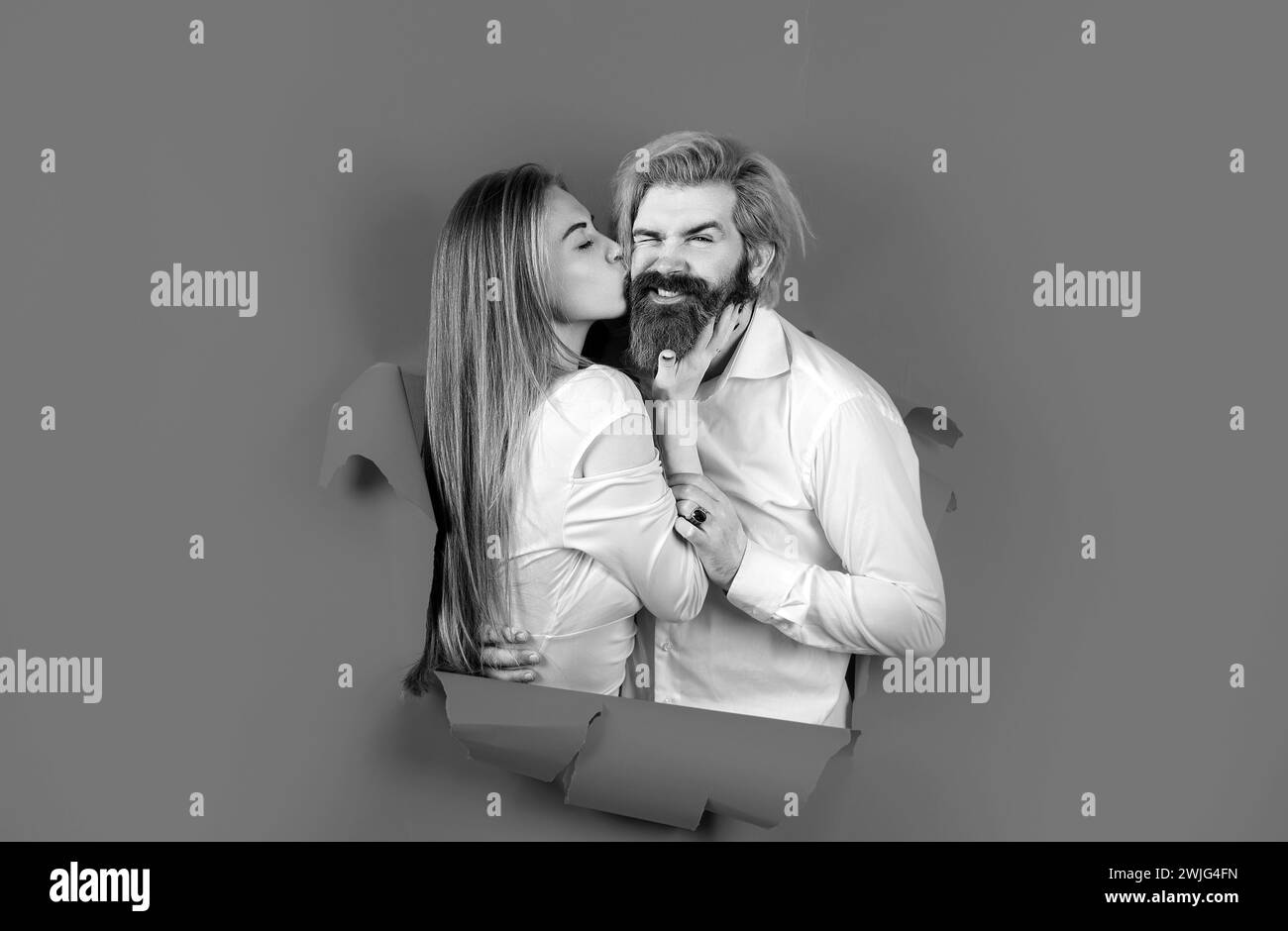 Couple through hole in blue paper, copy space for text or slogan. Discount and sale, people hole background. Surprised couple of bearded man and happy Stock Photo