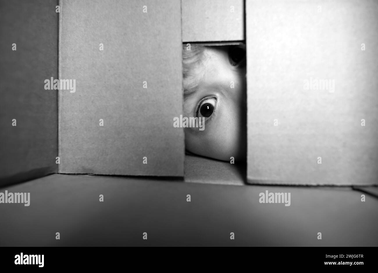 Child open carton delivery box, packaging open and closed cardboard box. Close up eyes looking. Child boy looking surprised into a gift. Stock Photo