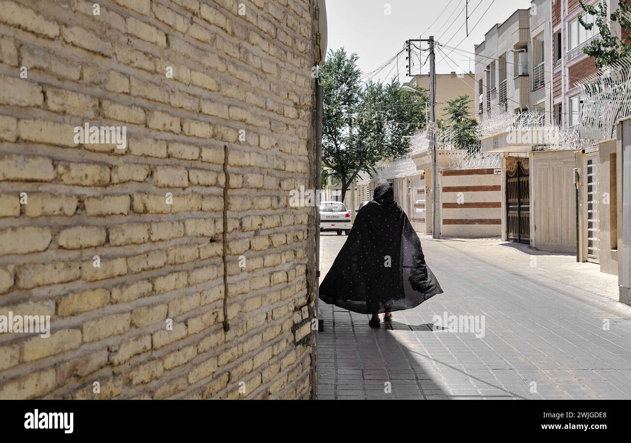 Isfahan, Iran, 06.30.2023:  An old women back, walking in iranian street, woman in traditional iranian black burqa Stock Photo