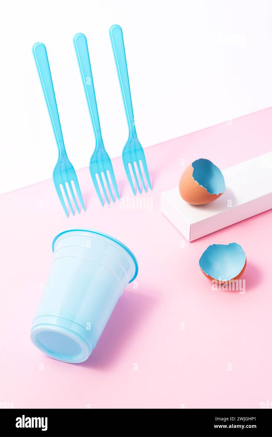 Blue painted easter egg shells with plastic forks and cup on pink background, high angle shot flat lay Stock Photo