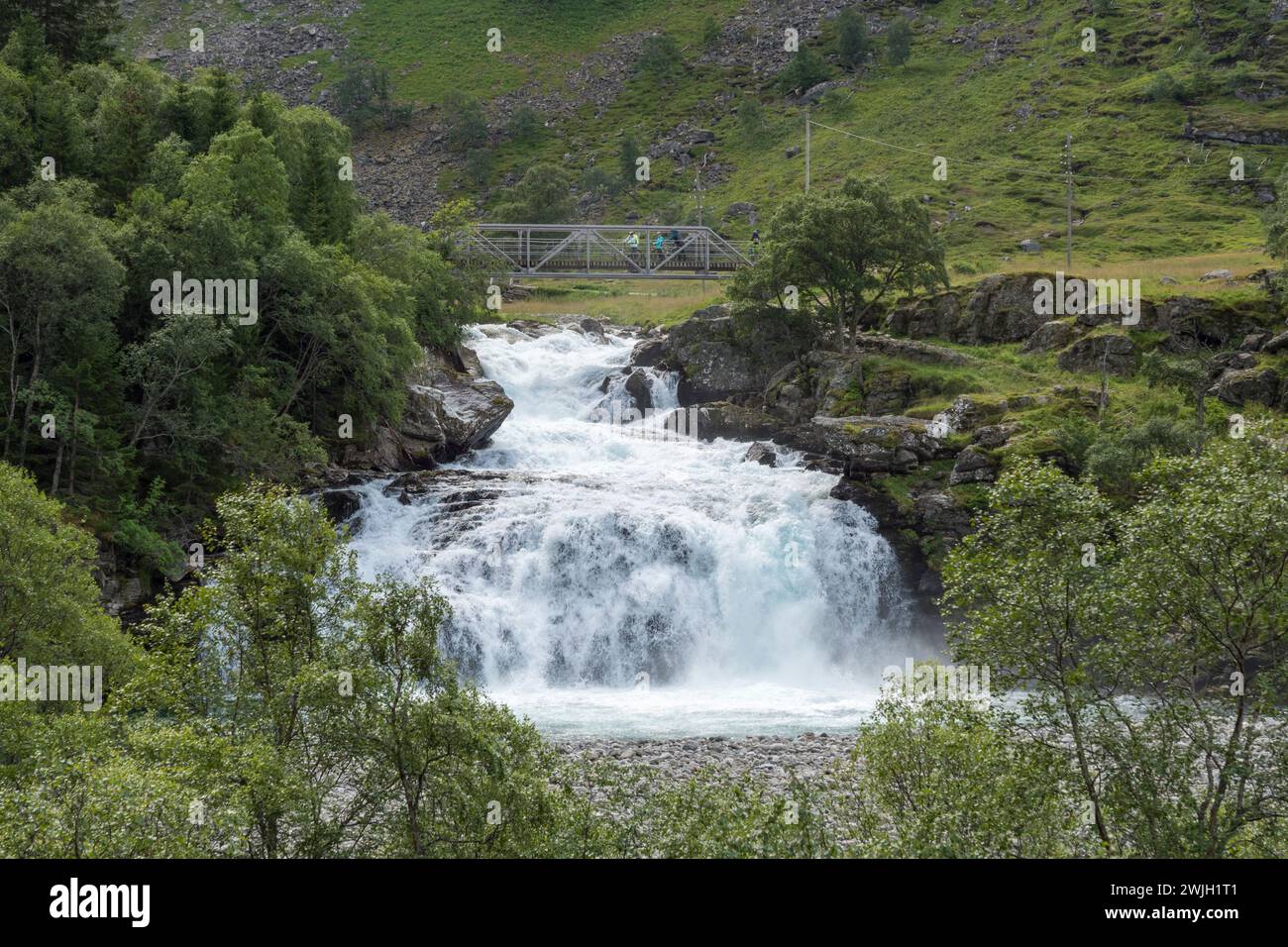 Cyclists cossing bridge over Kårdalsfossen Waterfall, Norway Stock Photo