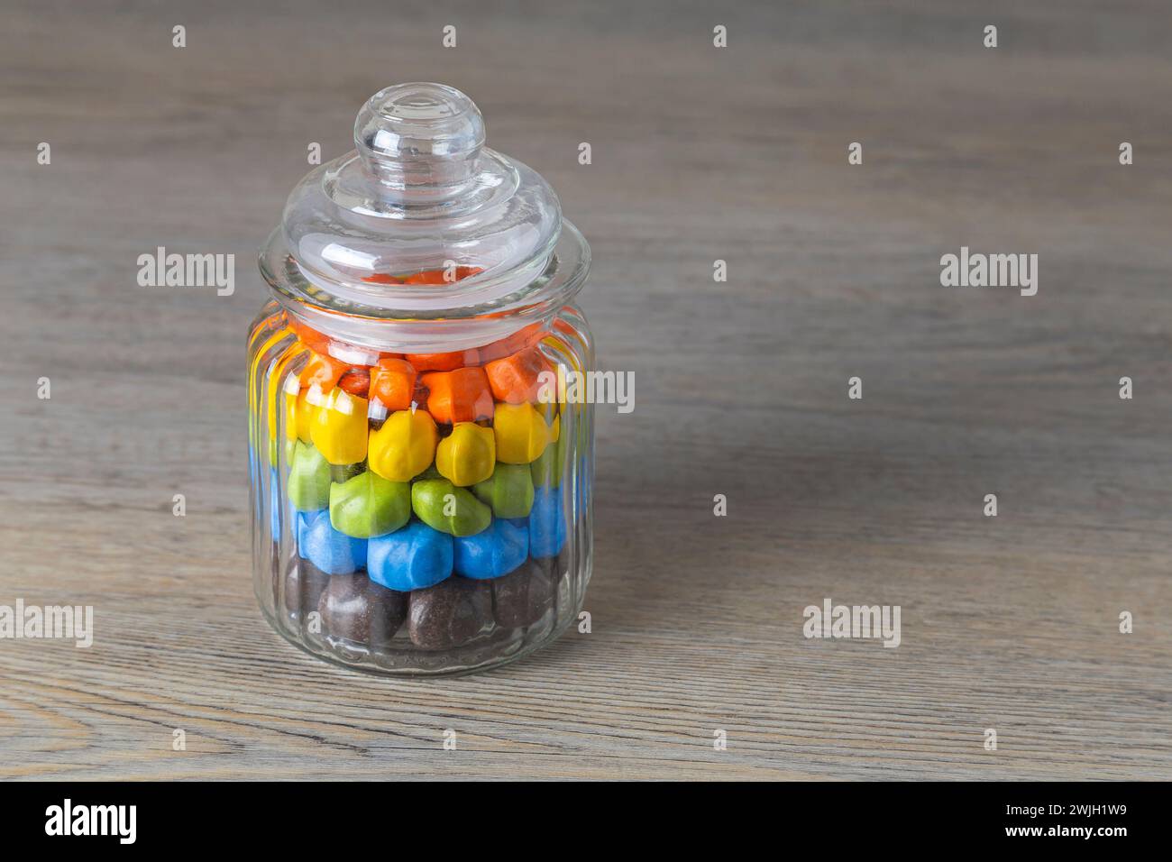 Milk chocolate Peanuts in a glass jar on a wooden table Stock Photo