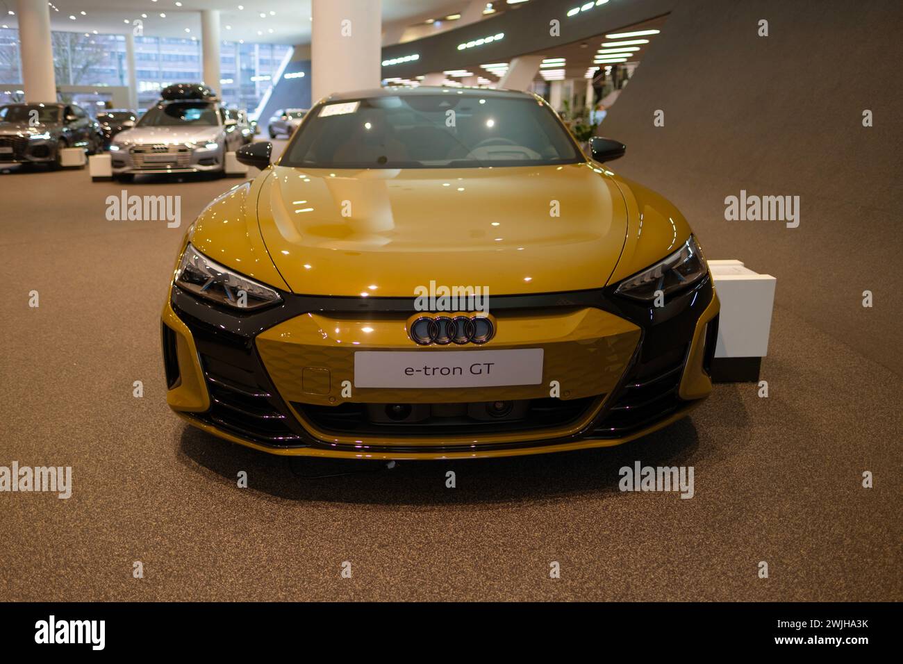 new Luxury Electric Car Audi e-tron GT, yellow limousine, four-door coupe in showroom, Automotive Innovation in automotive industry, Future Mobility s Stock Photo