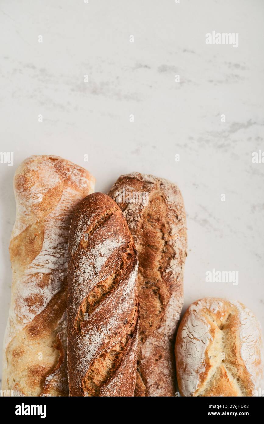 Assorted bakery products including loafs of bread,  baguette and rolls on light background, top view Stock Photo