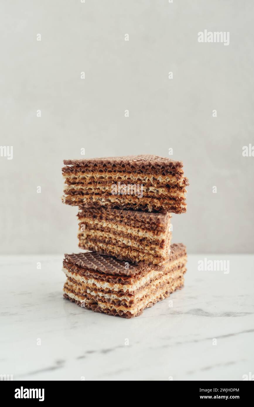 Waffle cake made of crispy waffle cakes with boiled condensed milk on a light  background, closeup Stock Photo