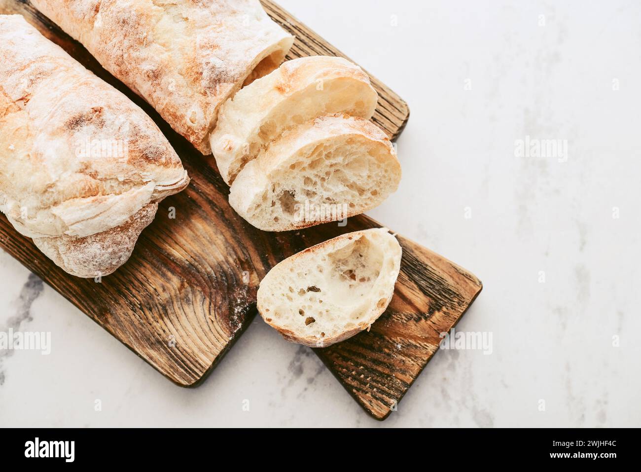 Rustic French sourdough baguettes on wooden cutting board, top view Stock Photo