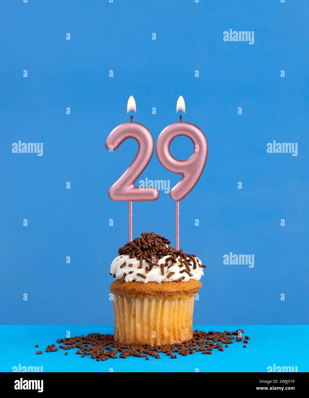 Birthday candle with cupcake on blue background - Number 29 Stock Photo