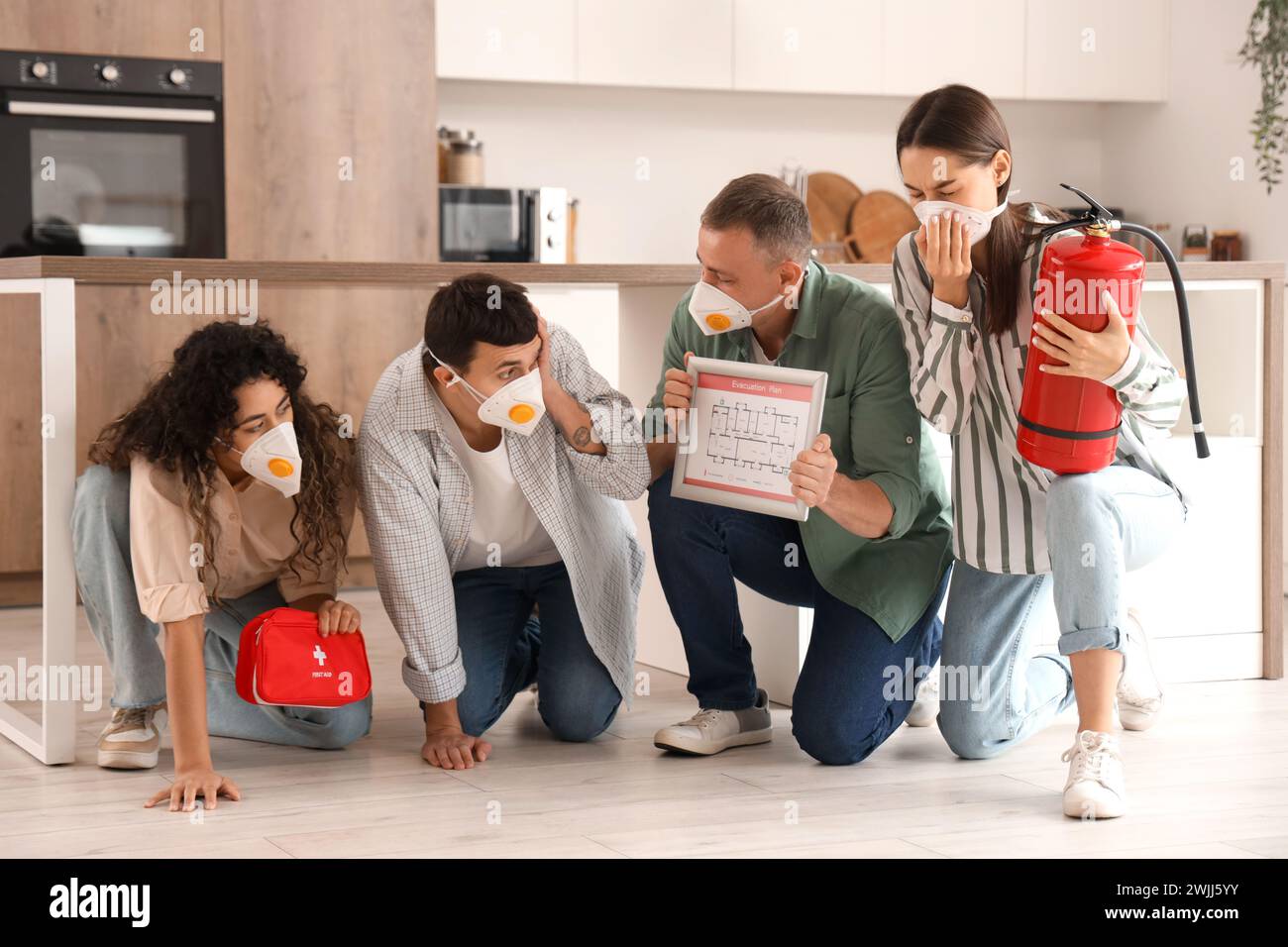 People with evacuation plan, first aid kit and fire extinguisher in burning kitchen Stock Photo