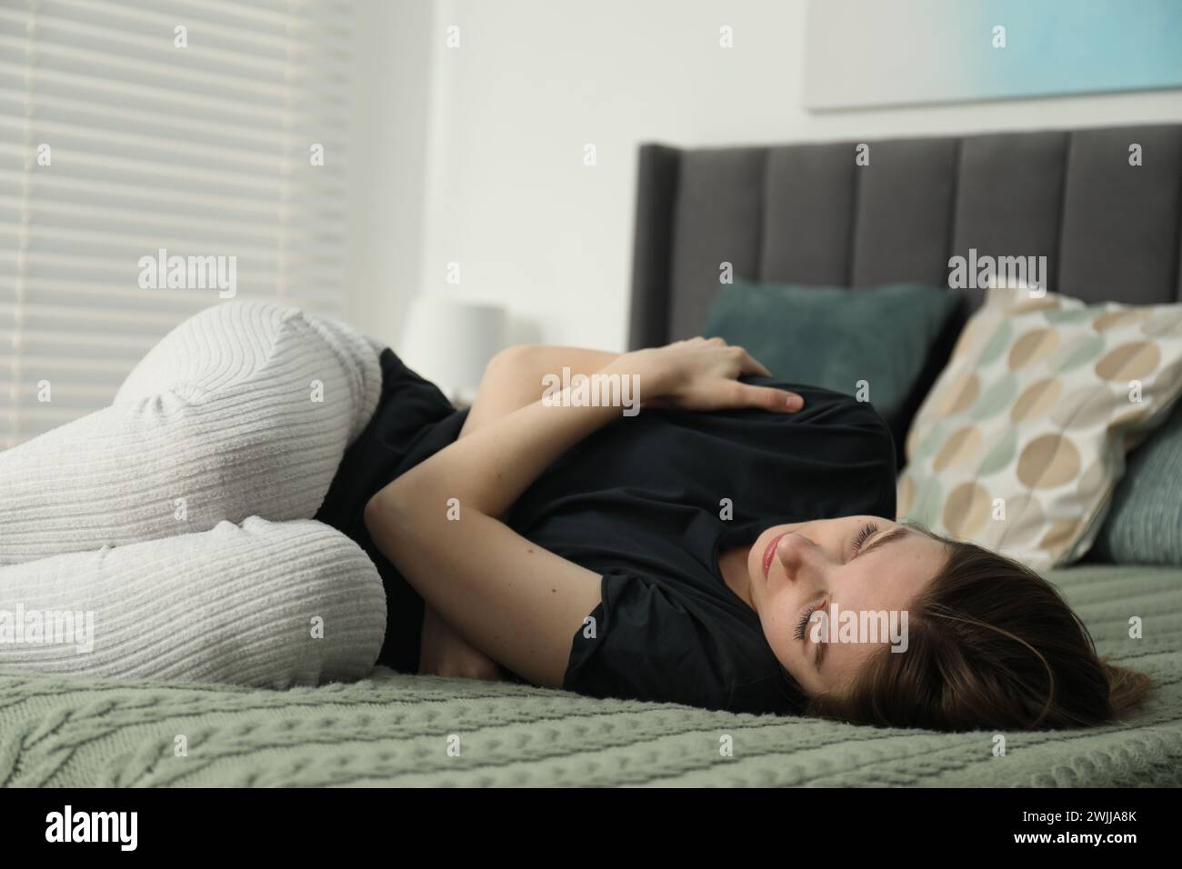 Sad young woman lying on bed at home Stock Photo - Alamy
