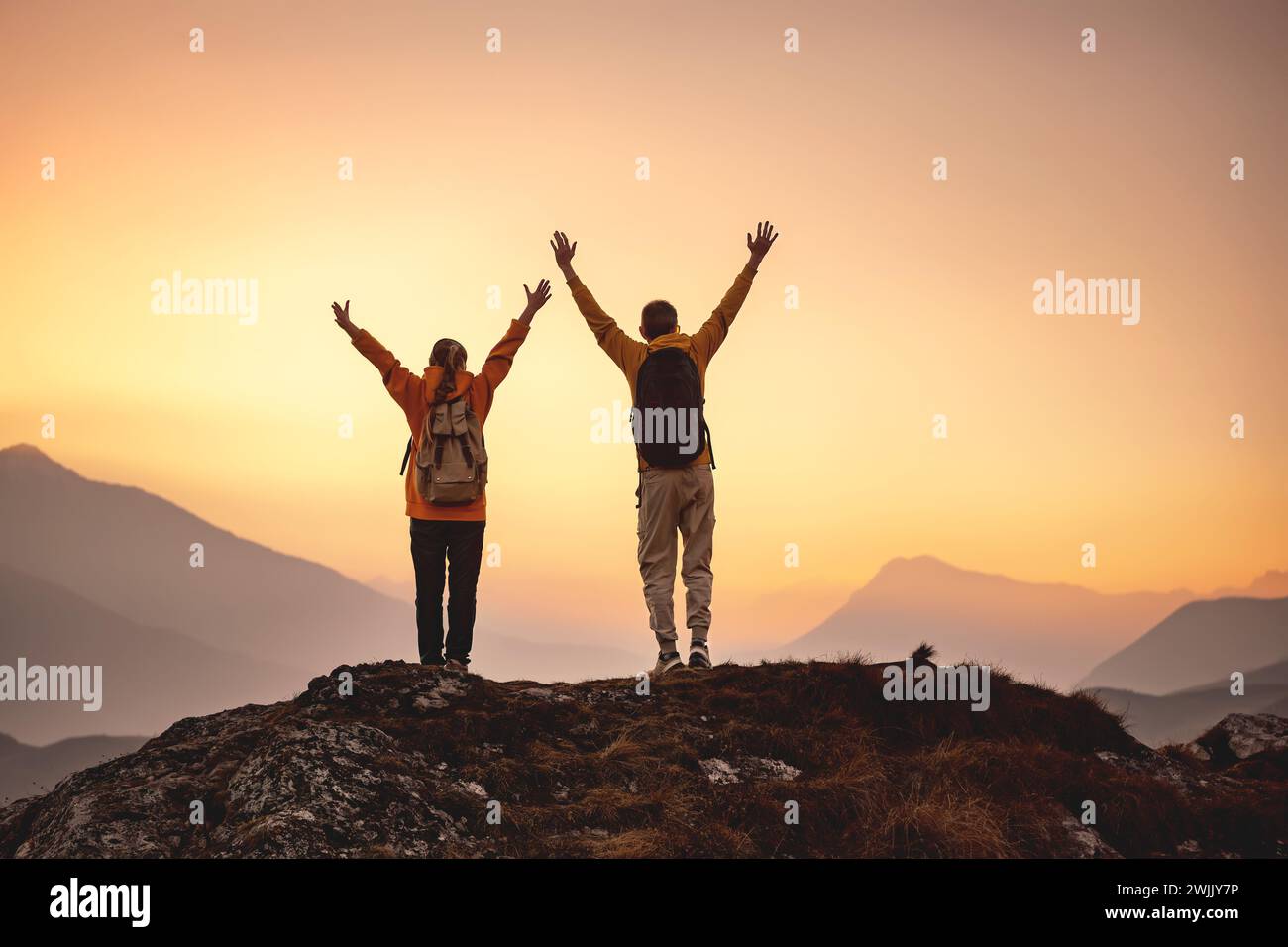 Two hikers are standing in winner pose at mountain top Stock Photo