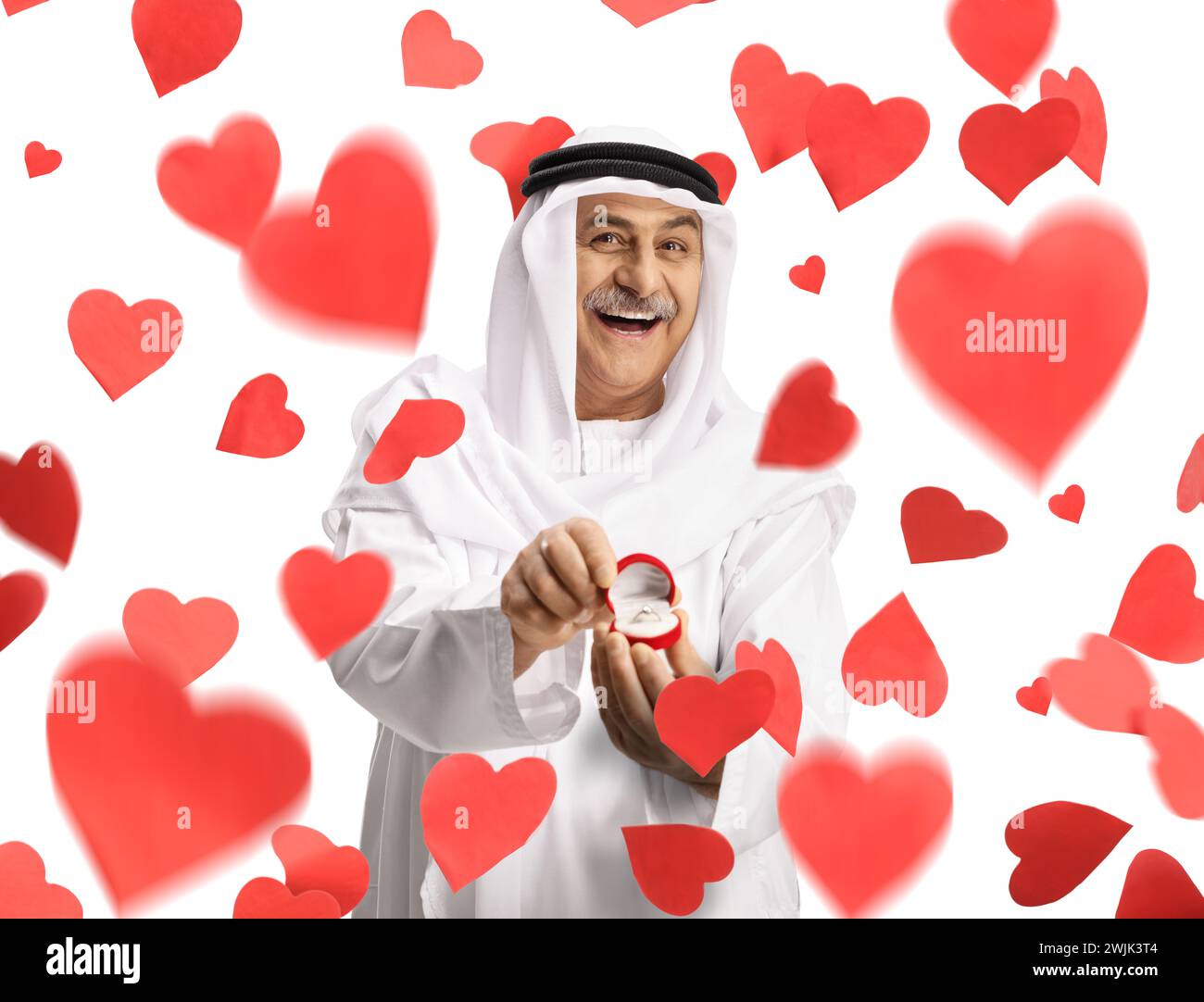 Smiling arab man holding an engagement ring in a box under falling hearts Stock Photo