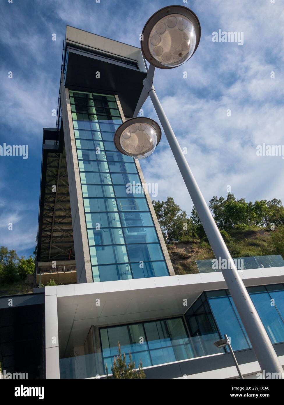 Upward view of a contemporary glass building with stylish street lamps and a clear blue sky. Stock Photo