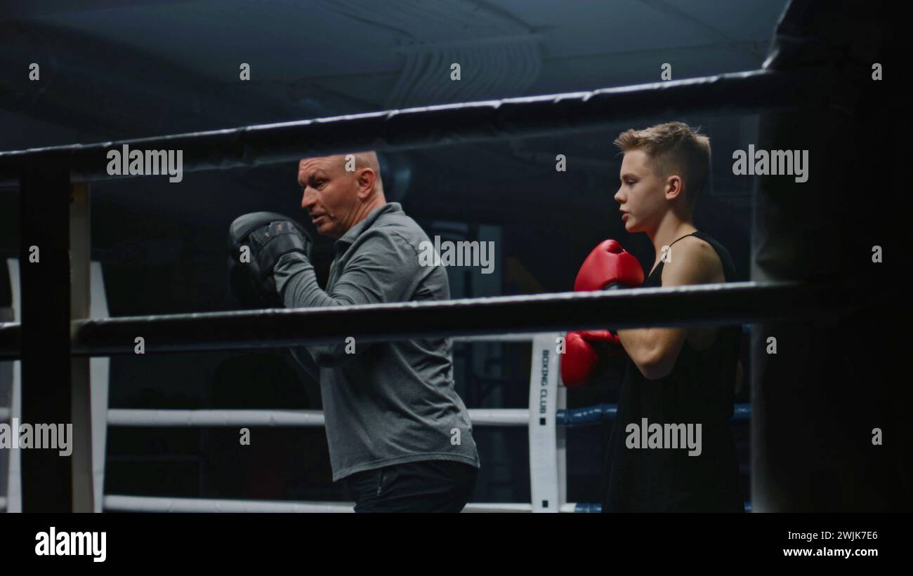 Professional coach teaches young boxer how to dodge punches on boxing