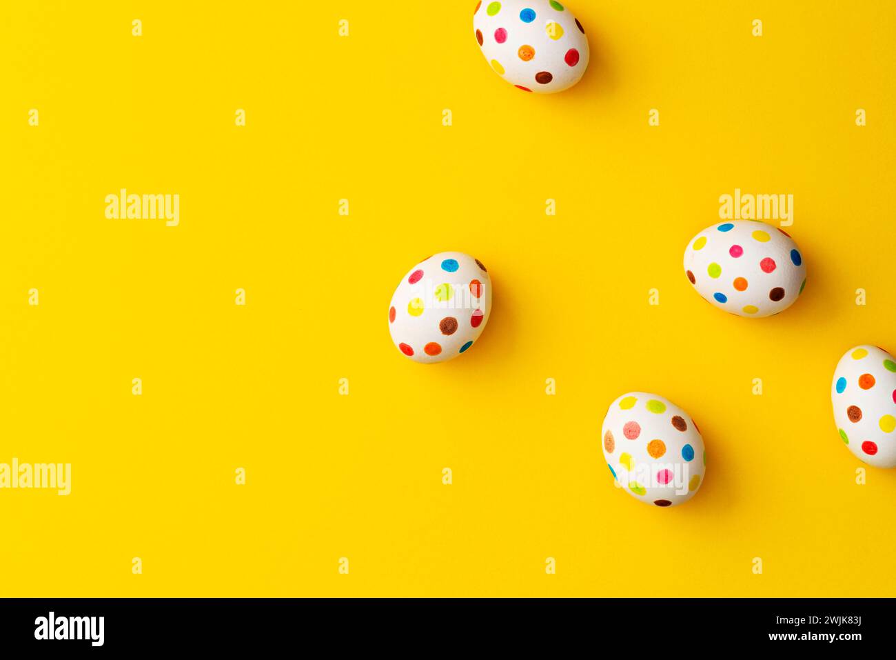 Spotty painted colorful easter eggs on yellow background. Directly above table top shot. Stock Photo
