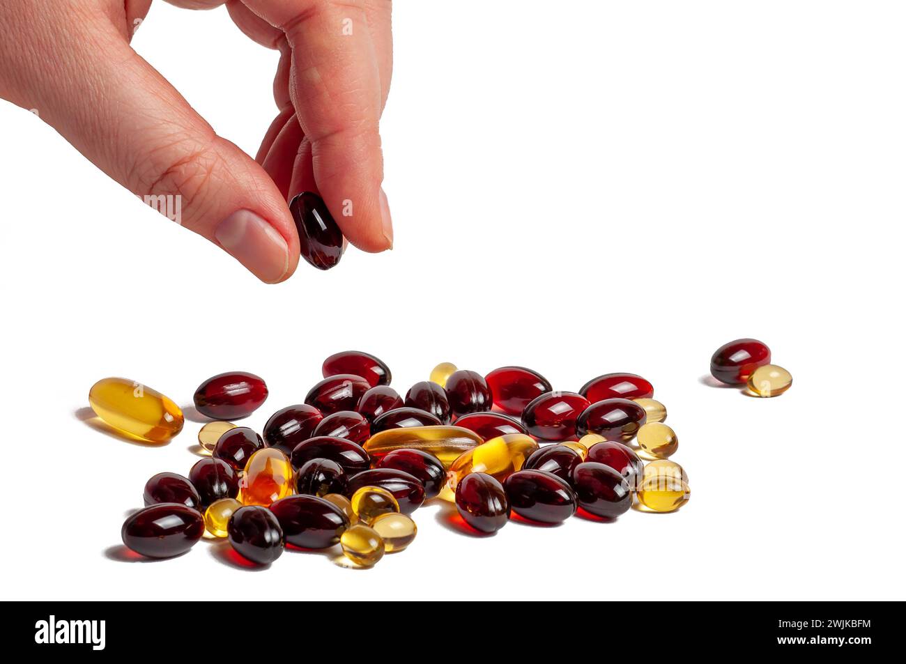 A hand picking up a supplement from a pile of various capsules. Stock Photo