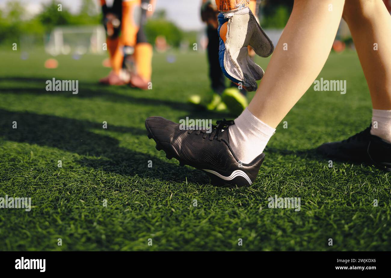 Soccer goalkeepers academy. Football goalie stretching legs at training session. Boy in soccer cleats and gloves in practice session Stock Photo