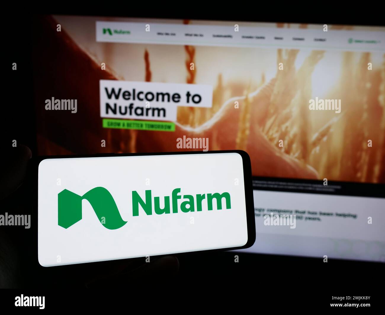 Person holding smartphone with logo of Australian agrochemical company Nufarm Limited in front of website. Focus on phone display. Stock Photo