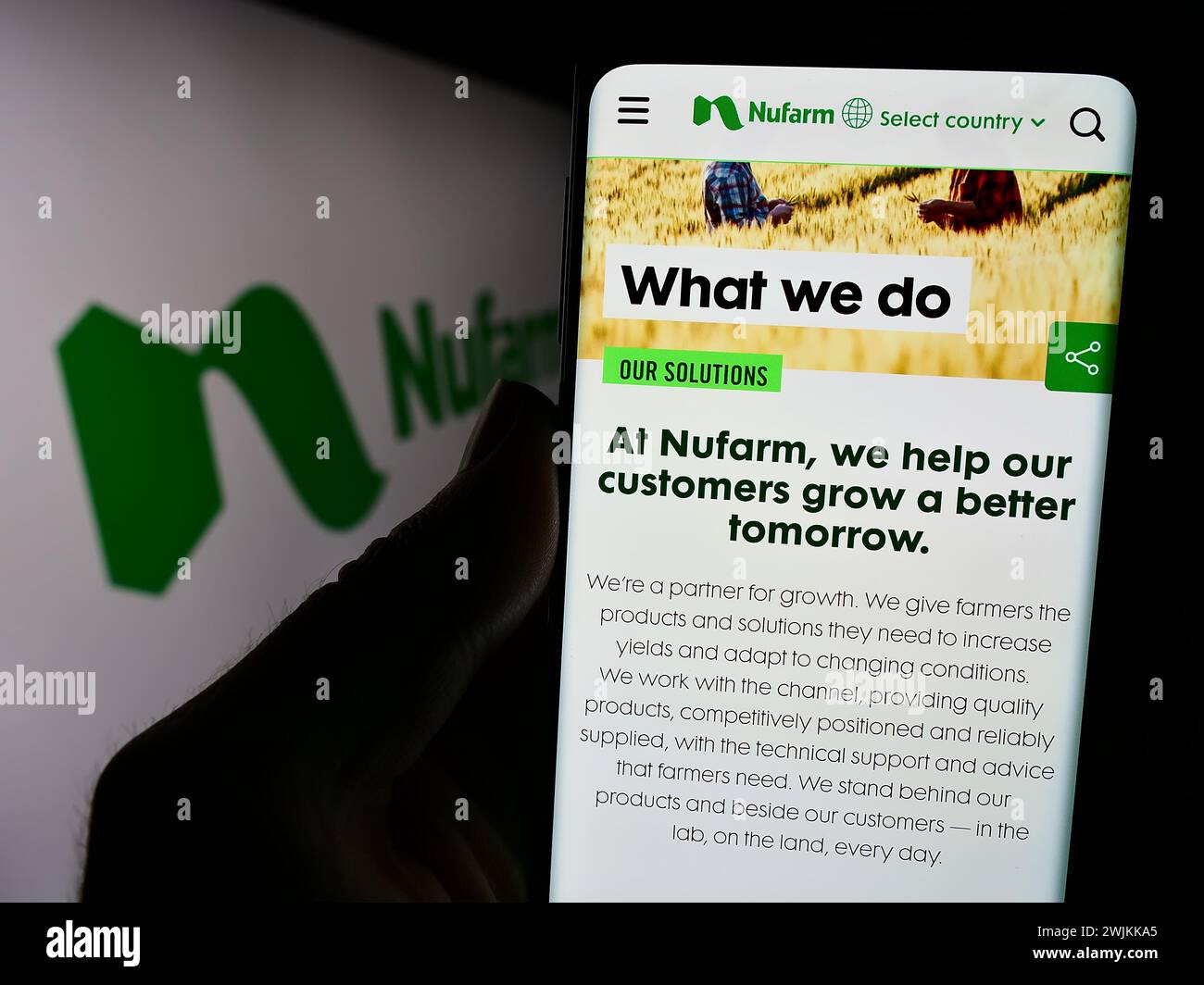 Person holding cellphone with website of Australian agrochemical company Nufarm Limited in front of logo. Focus on center of phone display. Stock Photo