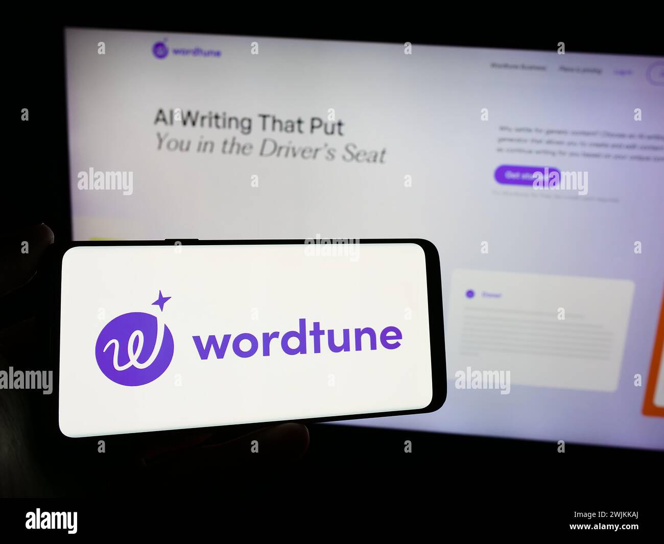 Person holding mobile phone with logo of artificial intelligence companion Wordtune (AI21 Labs) in front of web page. Focus on phone display. Stock Photo