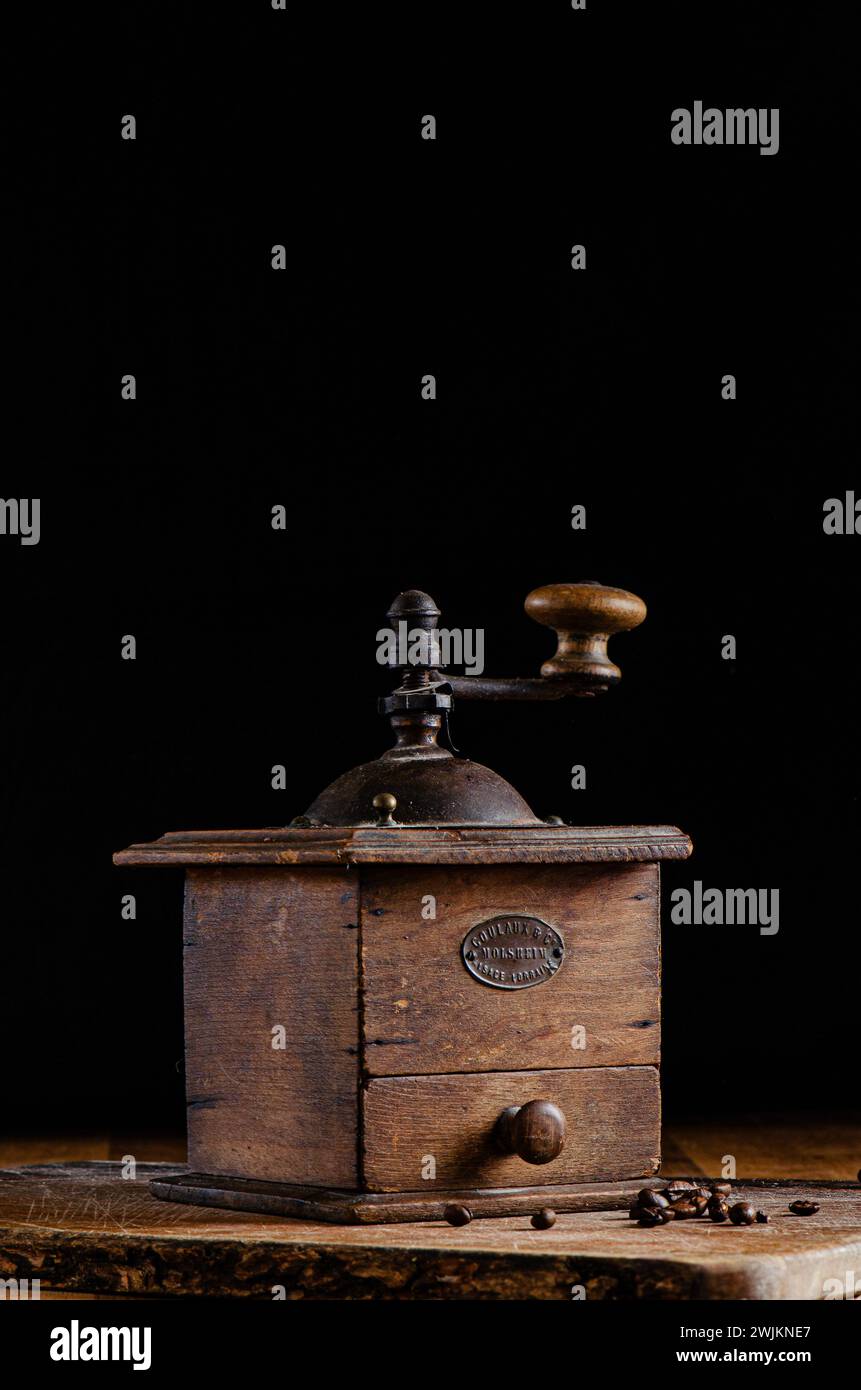 Old coffee grinder on wooden surface and dark background Stock Photo