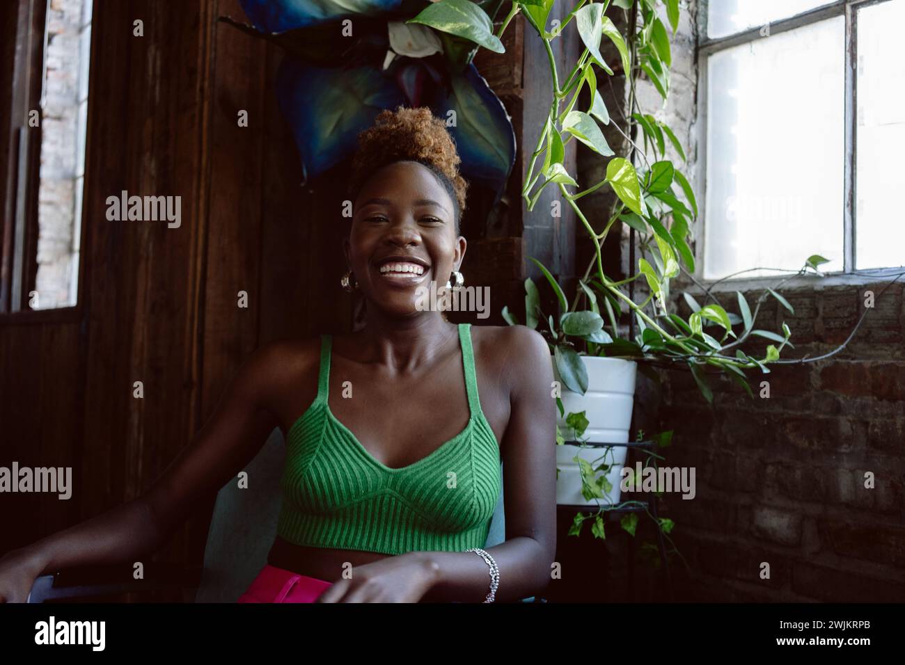 Young Black woman in colorful attire smiles at camera while laughing Stock Photo