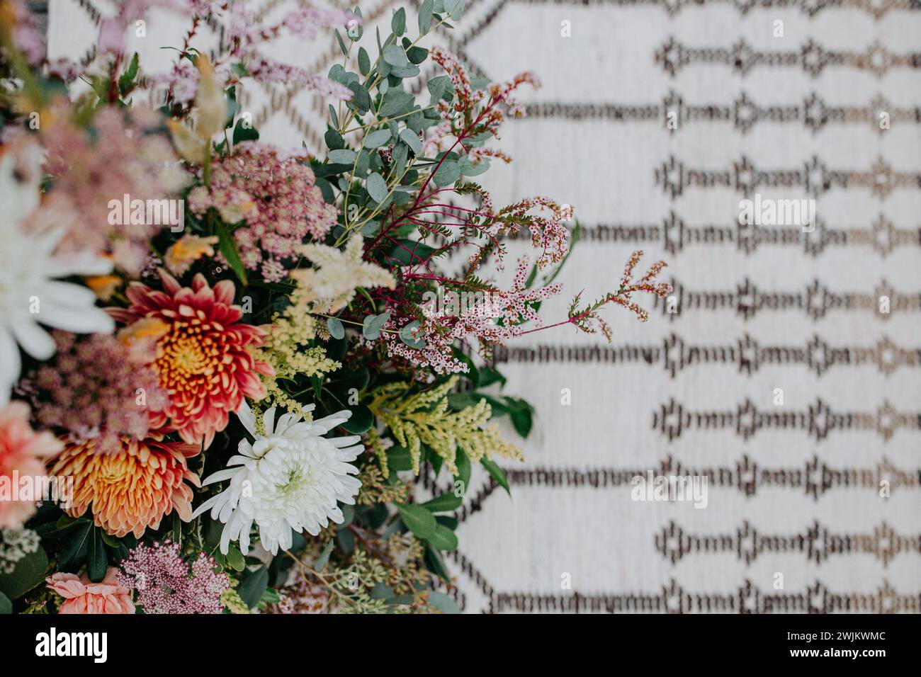 Looking down onto summer wedding bouquet against boho carpet Stock Photo