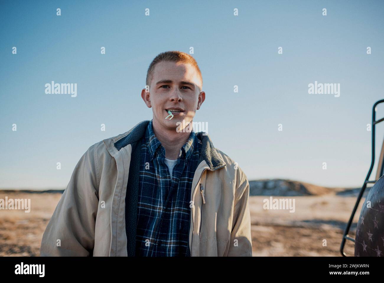 A candid portrait of a young man looking at the camera outdoors. Stock Photo