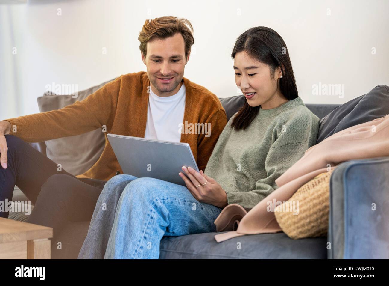 Adult couple using digital tablet while sitting on sofa Stock Photo