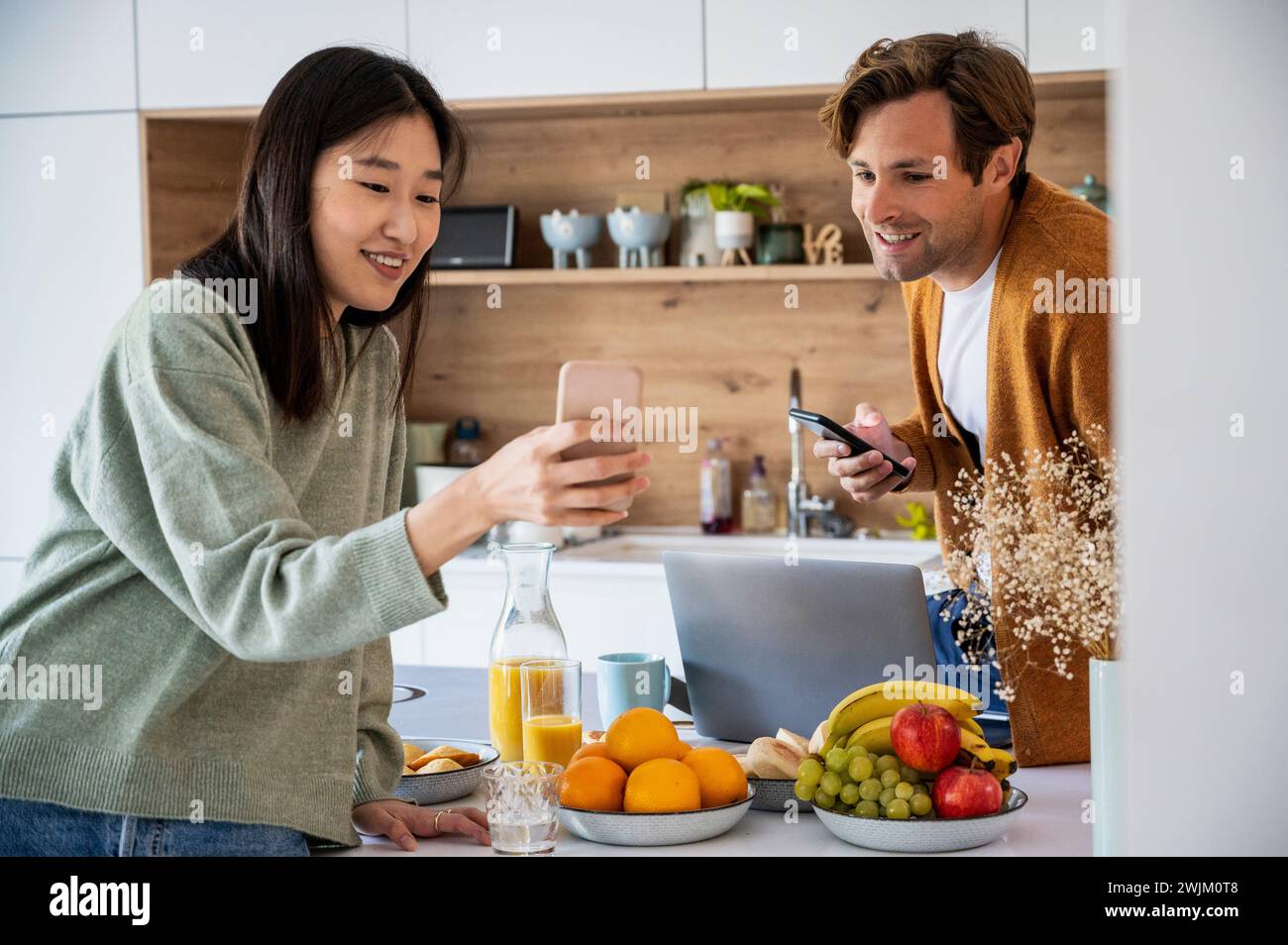 Adult couple talking over smart phone while having breakfast Stock Photo