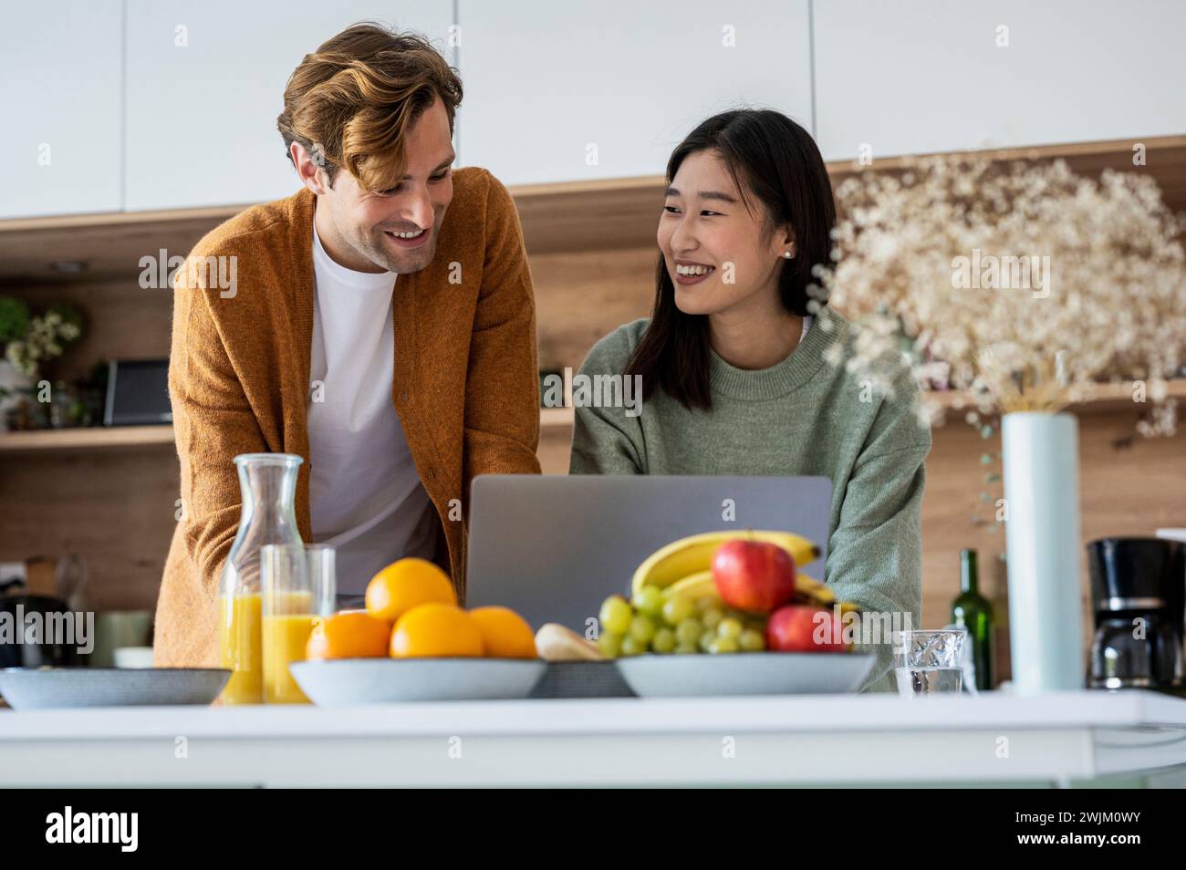 Adult couple using laptop together at kitchen counter Stock Photo