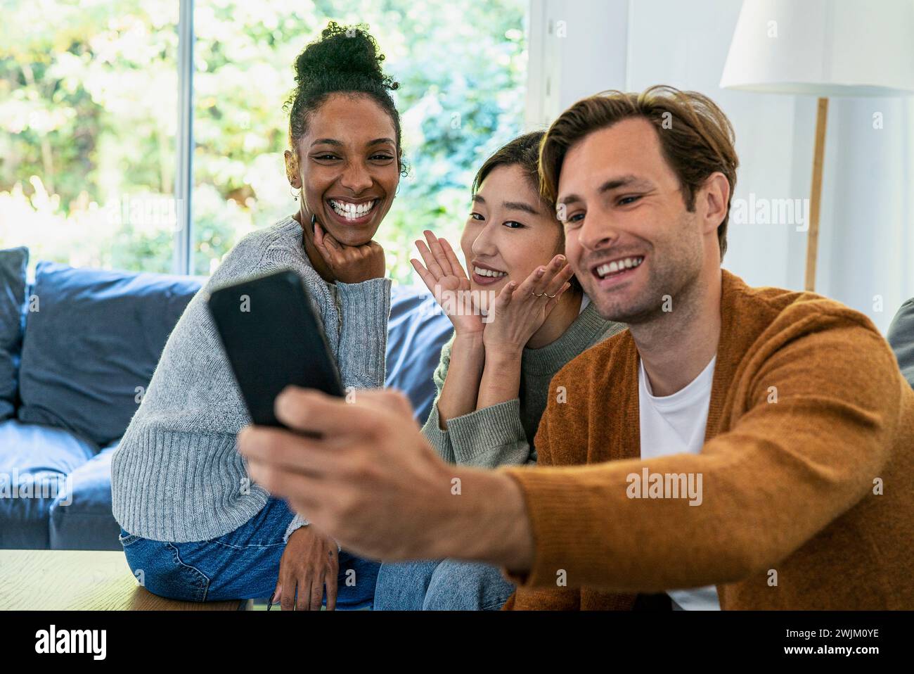 Small group of friends taking a selfie while sitting on sofa Stock Photo
