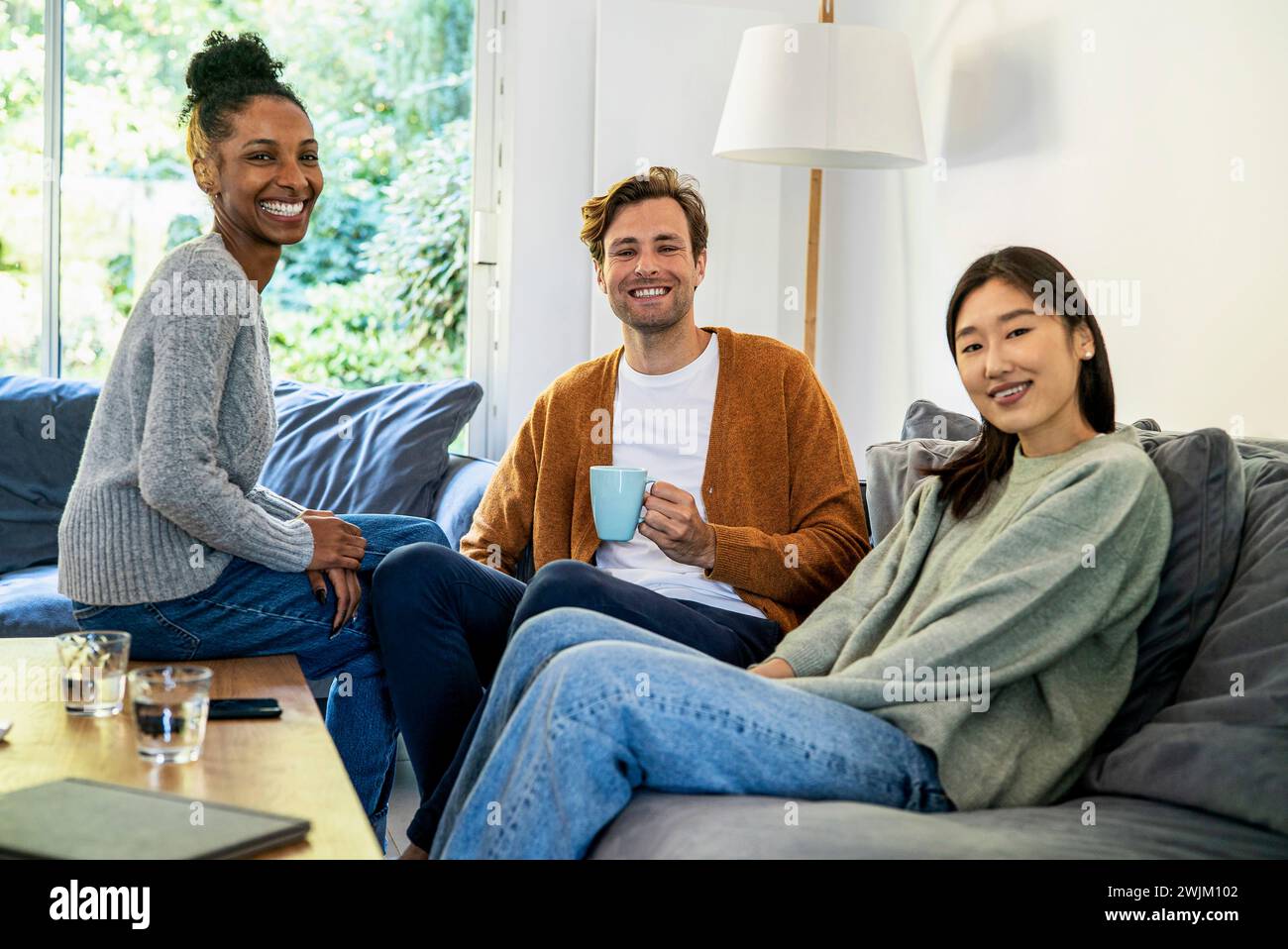 Small group of friends gathered in living room looking at the camera Stock Photo