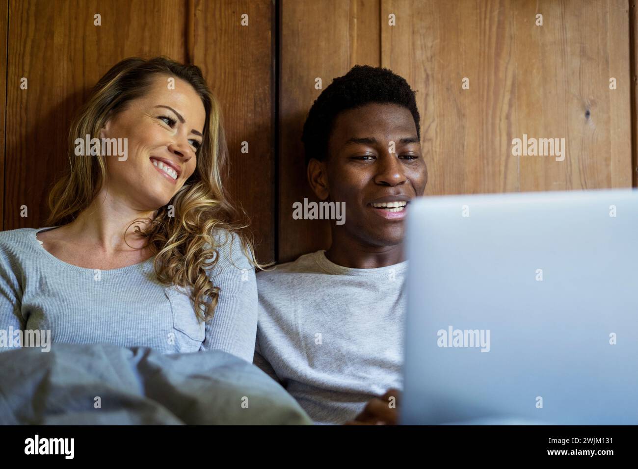 Happy couple using laptop while lying on bed Stock Photo