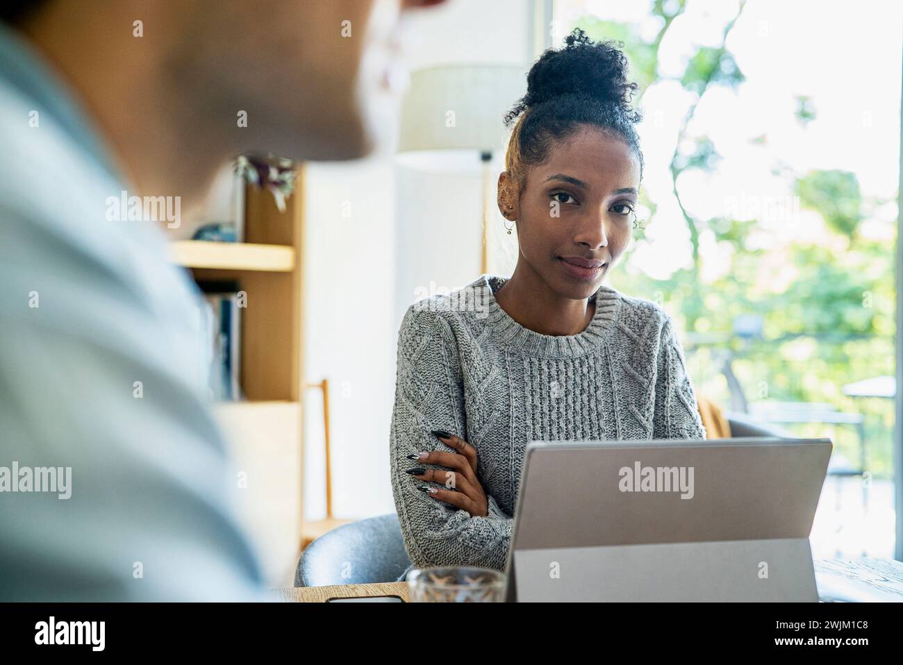 Young adult African American coworker looking at the camera while using digital tablet Stock Photo