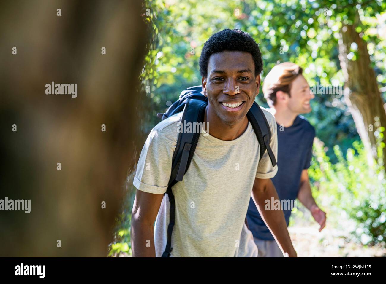 Young adult man wearing backpack looking at the camera during hiking with friends Stock Photo