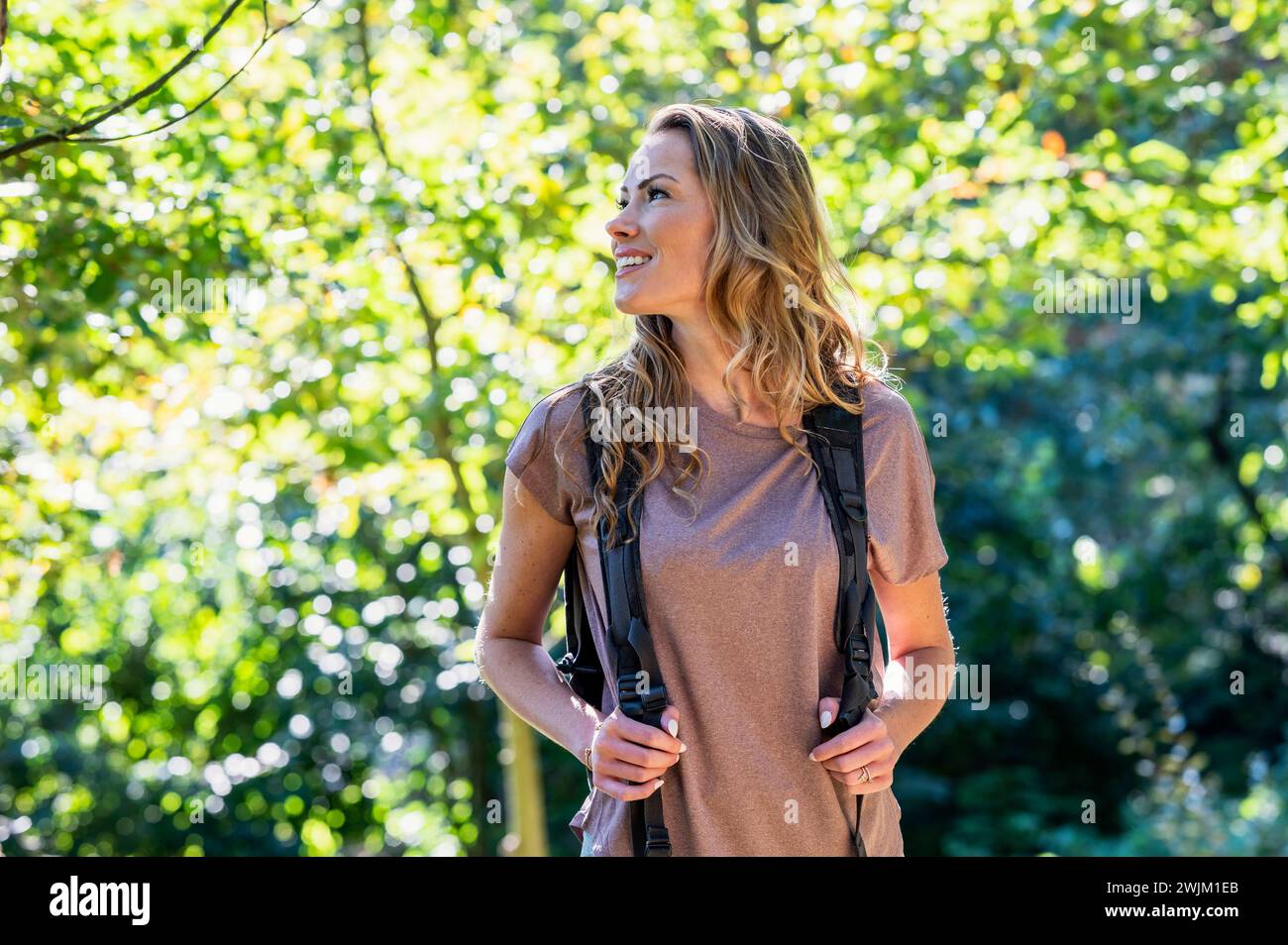 Beautiful woman wearing backpack while hiking in the woods Stock Photo