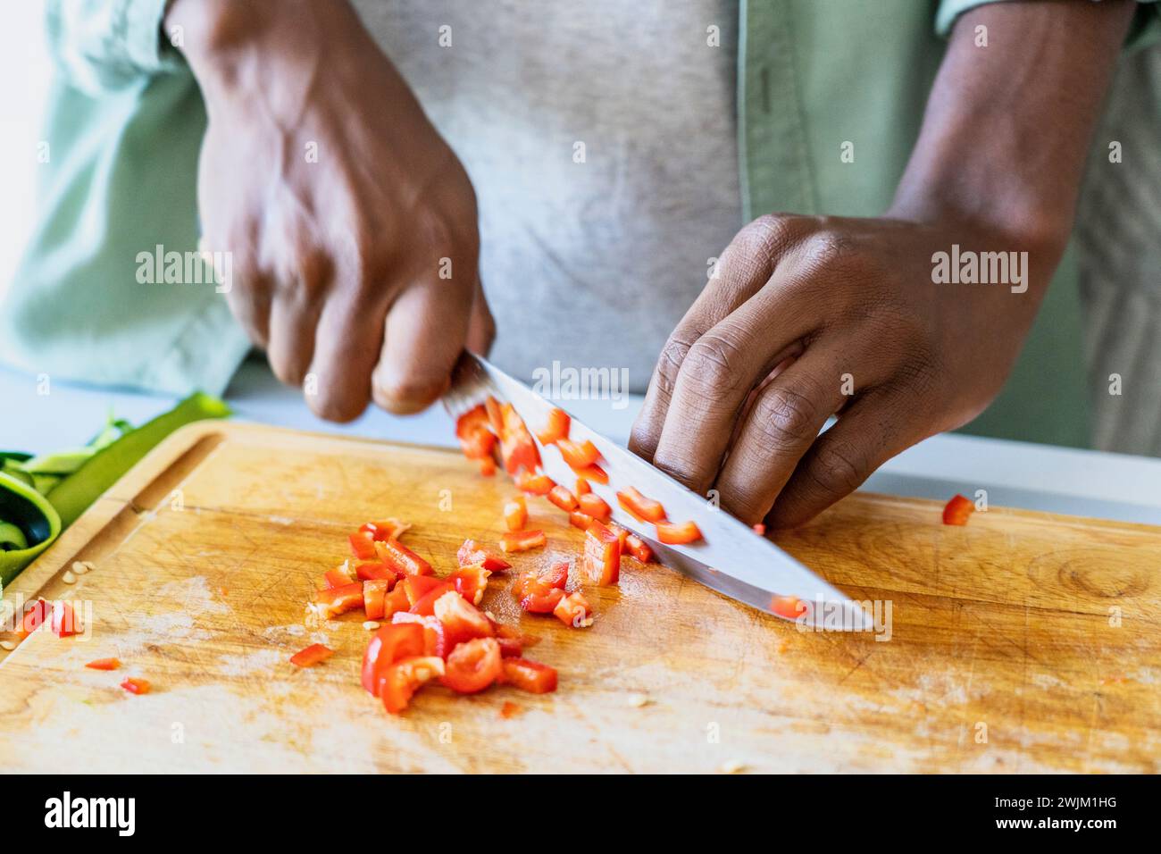 Close up of man's hands cutting vegetable with sharp knife on cutting board Stock Photo